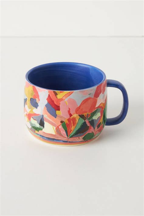 A Colorful Flowered Mug Sits On A White Surface With A Blue Rim And Handle