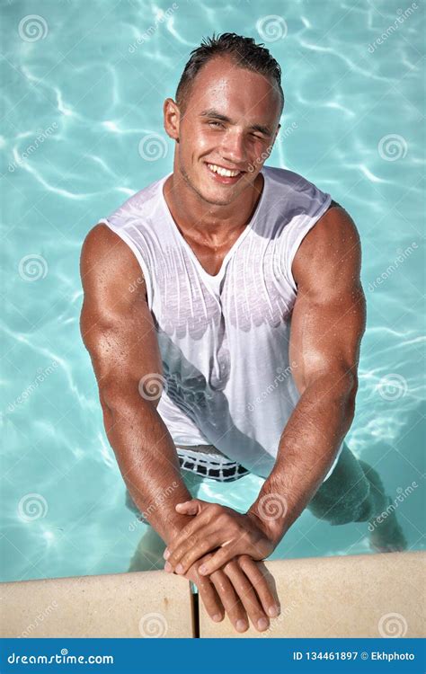 Muscular Young Wet Man In Swimming Trunks And White Tank Top Posing In Outdoor Pool Stock Image