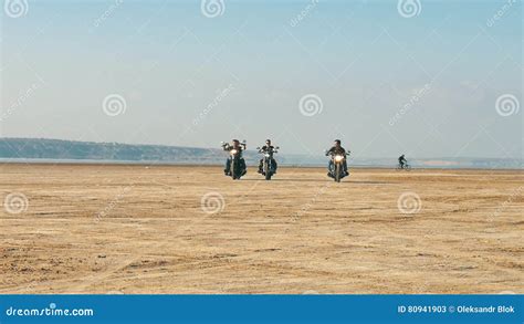 Three Motorcyclists Riding Near Sandy Beach In Desert From Far Away