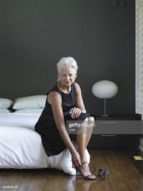 Mature Woman Sitting On Bed Fixing Shoe Portrait Photo Getty Images