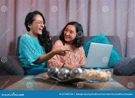 mom and daughter watching a laptop sitting on the sofa at home the two make expressions when