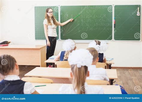 Teacher Near Blackboard Teaching Children Math Or Geometry Holding