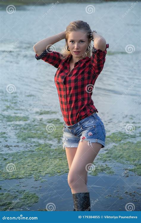 A Young Girl In Short Shorts And Rubber Boots Went Into The River Stock