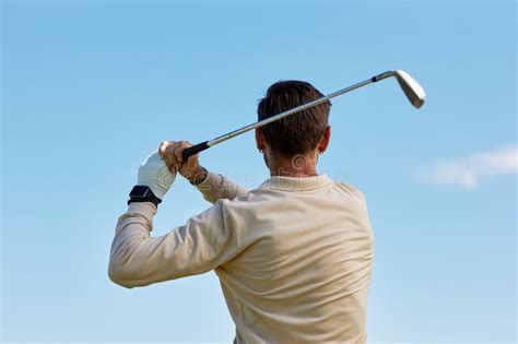 Back View Of Man Swinging Golf Club Against Blue Sky Stock Image