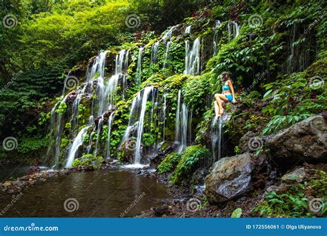 Young Caucasian Woman Sitting On The Rock And Enjoiyng Waterfall