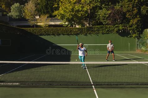 Senior African American Couple Playing Tennis On Tennis Court Stock