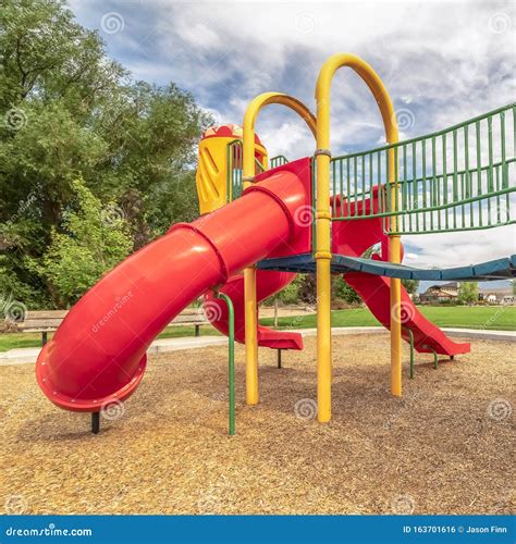 Square Close Up View Of The Colorful Playground With Red Closed Tube Slide At A Park Stock Photo