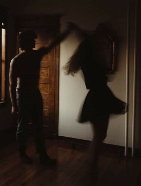 A Man Standing Next To A Woman In Front Of A Door With Her Arms