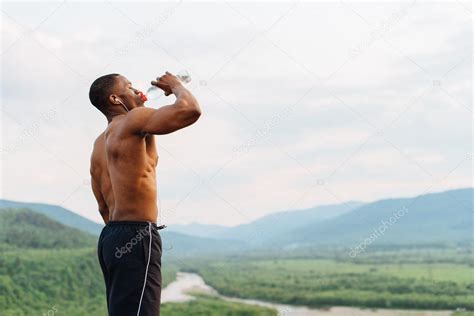 Сексуальный африканский мускулистый мужчина пьет воду после спортивных тренировок Захватывающий