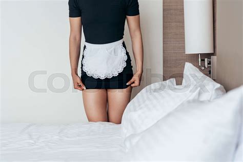 Cropped View Of Maid In White Apron Standing Near Bed In Hotel Room