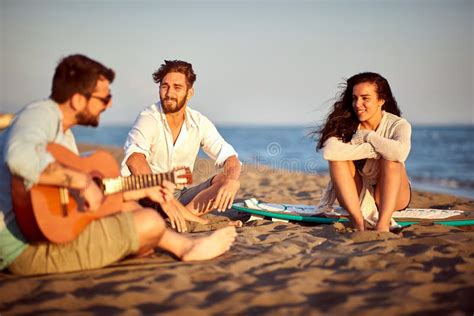 一群白人朋友坐在海滩上，享受着日落时的微笑 库存图片 图片 包括有 海洋 男性 幸福 唱歌 节假日 190878625