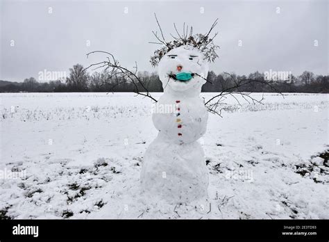 Funny Snowman On Snowy Field Wearing A Medical Face Mask Against