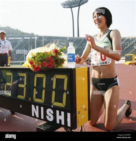 tokyo japan japanese sprinter chisato fukushima smiles next to a trackside clock showing the
