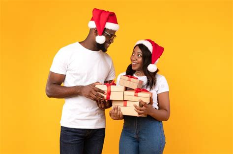 African American Couple Holding Christmas Ts Boxes Over Yellow