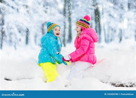 Kids Playing In Snow Children Play Outdoors In Winter Snowfall Stock