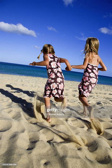 Sisters Running On Beach Holding Hands Rear View High Res Stock Photo