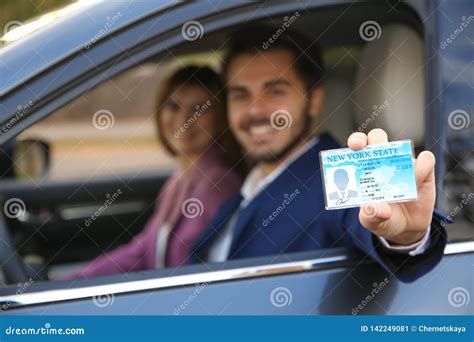 Young Man Holding Driving License In Car With Passenger Stock Image