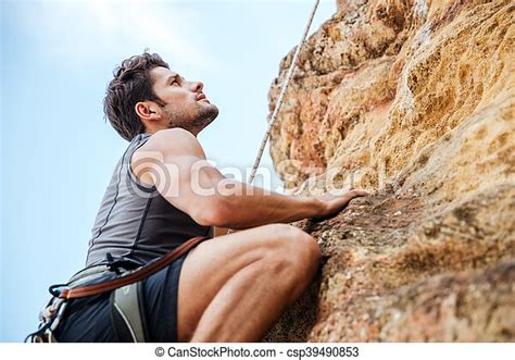Young Man Climbing A Steep Wall In Mountain Young Fearless Man