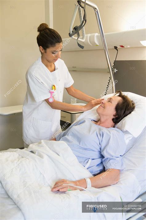 Female Nurse Attending Patient On Hospital Bed Mixed Race Person Resting Stock Photo