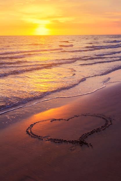 Premium Photo Heart Shape Drawn On A Sandy Beach At Sunset