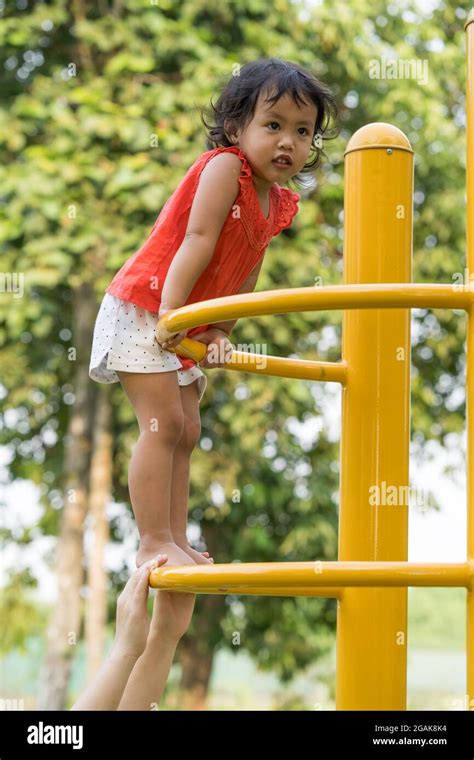 Cute Thai Girl Playing On The Playground Against A Blurred Background