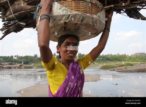 a local indian woman carries her load of wood in a basket on her head in hampi northern