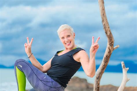 Beautiful Mature Aged Woman Doing Yoga On A Desert Tropical Beach Stock