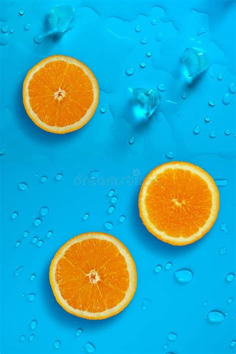 Fresh Juicy Slices Of Orange And Ice Cubes On The Bright Blue