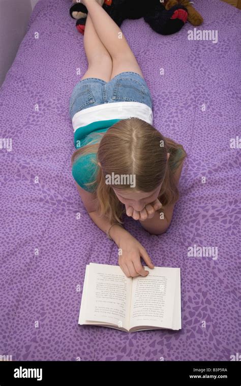 Young Girl Lying On Bed Sur Son Ventre La Lecture Dun Livre Photo