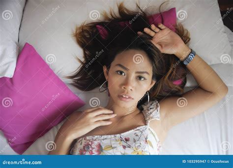 Portrait Of Young Attractive And Beautiful Asian Woman Lying On Bed At Bedroom Posing Looking To