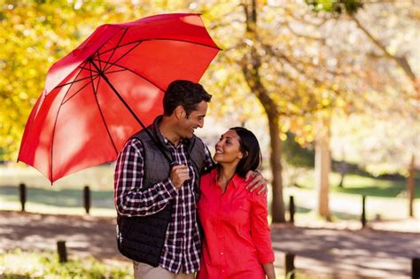 Premium Photo Couple Holding Umbrella At Park