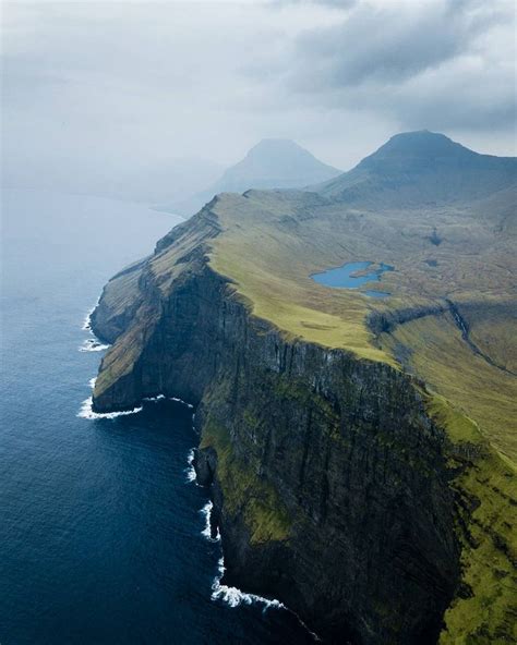 An Aerial View Of The Cliffs And Ocean In Iceland With Green Grass On