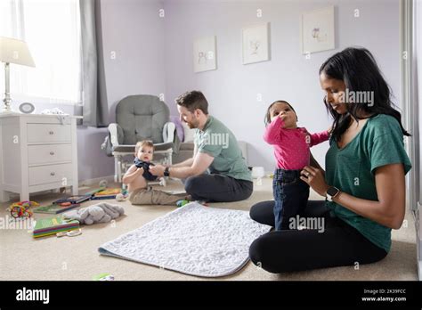 Parents Changing Kids Clothes On Bedroom Floor Stock Photo Alamy