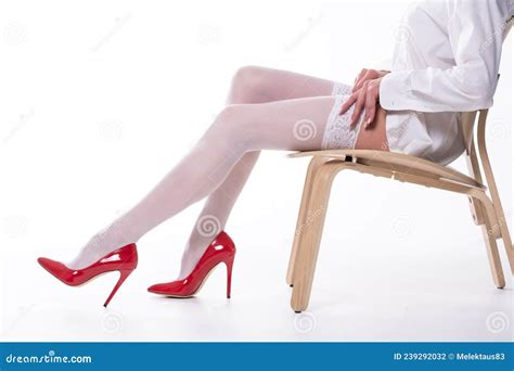 Kobieta Z Pięknymi Nogami W Białych Pończochach I Czerwonych Butach Siedzi Na Krześle Na Białym