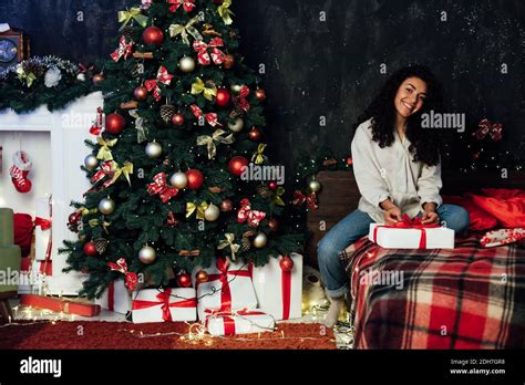 Beautiful Brunette Woman Opens Presents At Christmas Tree With Lights