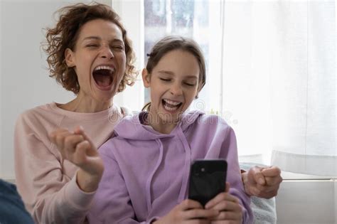 Excited Mom And Teenage Girl Daughter Winning Using Smartphone Stock