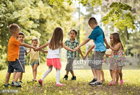 Group Of Small Kids Playing Ringaroundtherosy In The Park High Res