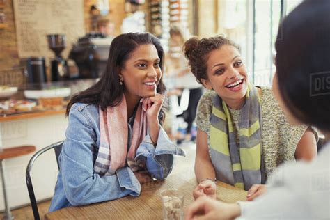 Smiling Women Friends Talking At Cafe Table Stock Photo Dissolve