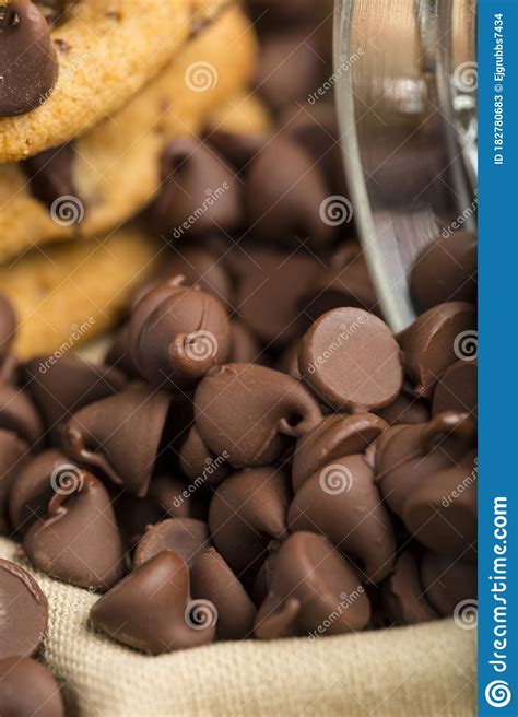 Delicious And Tempting Pile Of Dark Chocolate Chips Morsels And Chocolate Chip Cookie In A Glass