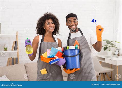 African American Couple Holding Cleaning Tools And Detergents Stock