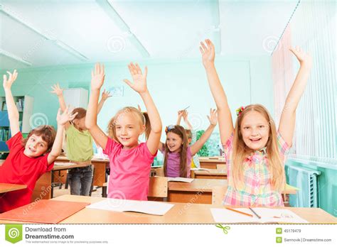 Happy Kids With Arms Up Sit In Classroom Rows Stock Photo