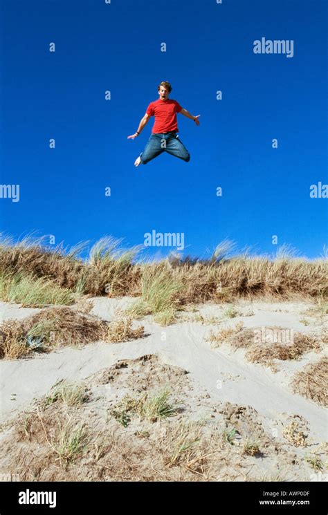 Young Man Leaping From A Sand Dune Braunton Burrows Devon Uk Stock