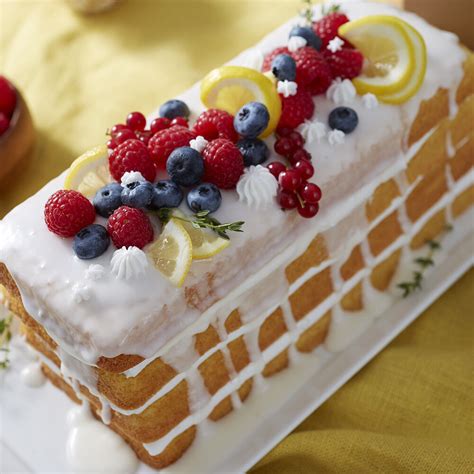 A loaf cake on a platter with a few slices cut, garnished with lemon slices. Summer Fruit Loaf Cake | Wilton