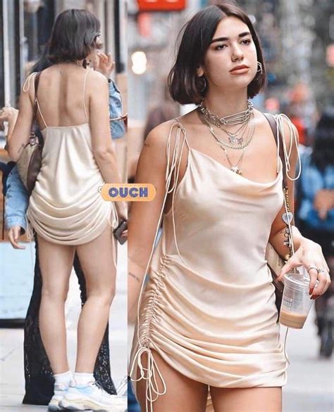 A Woman Walking Down The Street In A Tan Dress
