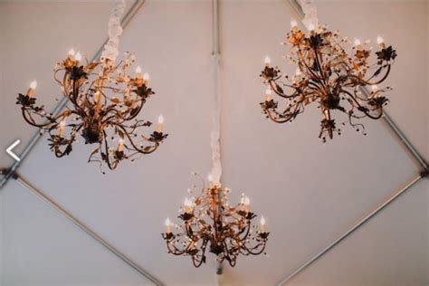 Two Chandeliers Hanging From The Ceiling In A Room With White Walls And Flooring
