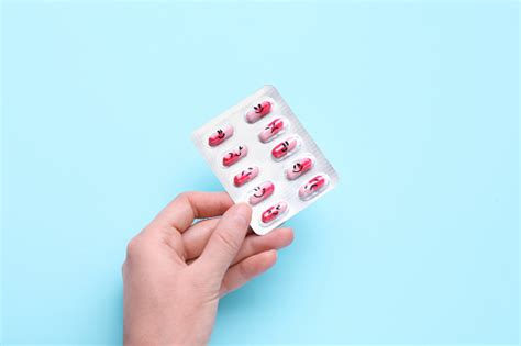 Woman Holding Antidepressants With Different Emoticons On Light Blue