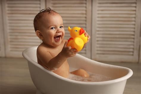 Um Bebê De 11 Meses Tomando Banho Em Uma Banheira De Bebê Branca Com Patinhos De Borracha Foto