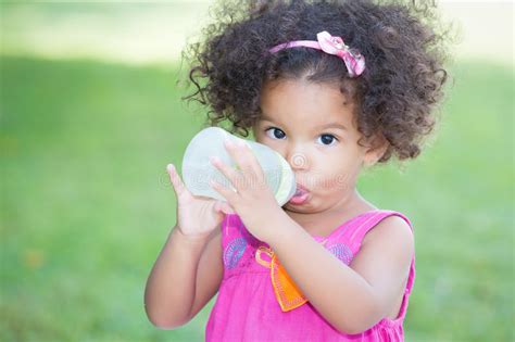 Cute Latin Girl Drinking From A Baby Bottle Stock Image