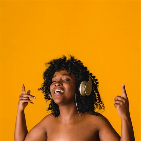 Nackte schwarze junge frau im kopfhörer im studio singt Kostenlose Foto