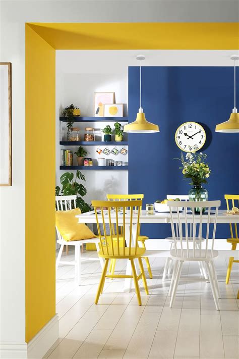 A Dining Room With Yellow And White Chairs Blue Walls And A Clock On